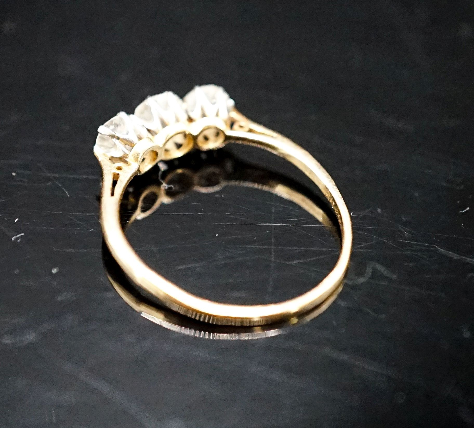 A yellow metal and three stone diamond ring, size M, gross 1.9 grams.